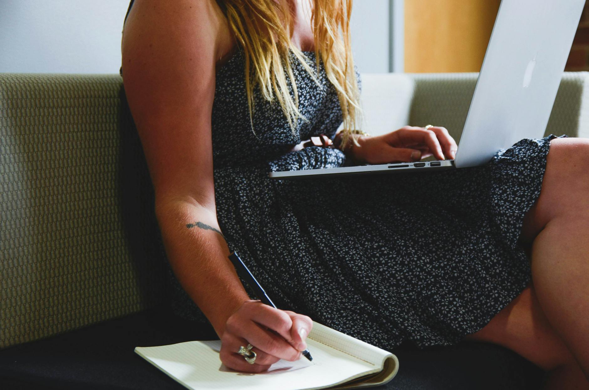woman working in front of her laptop while making a note
