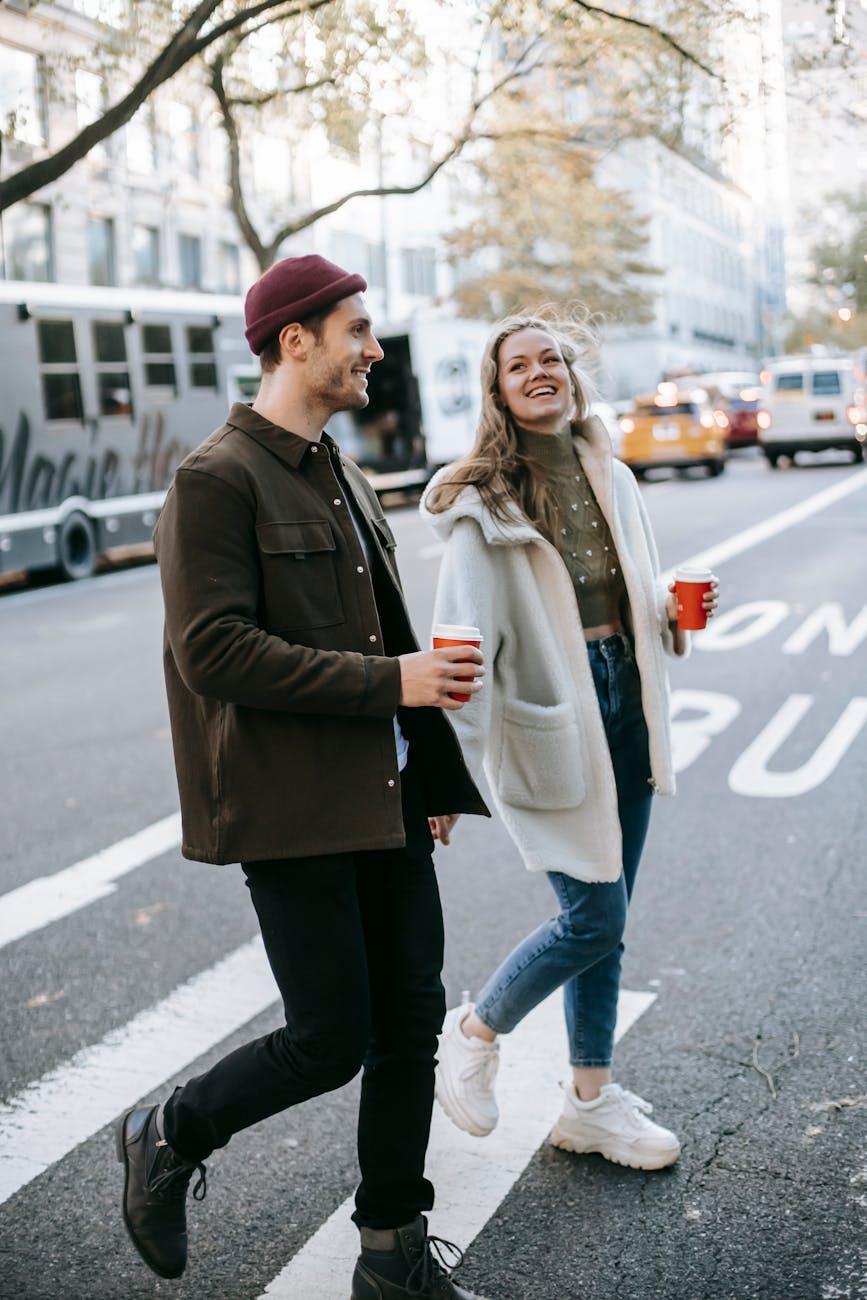 couple walking on street with coffee cups